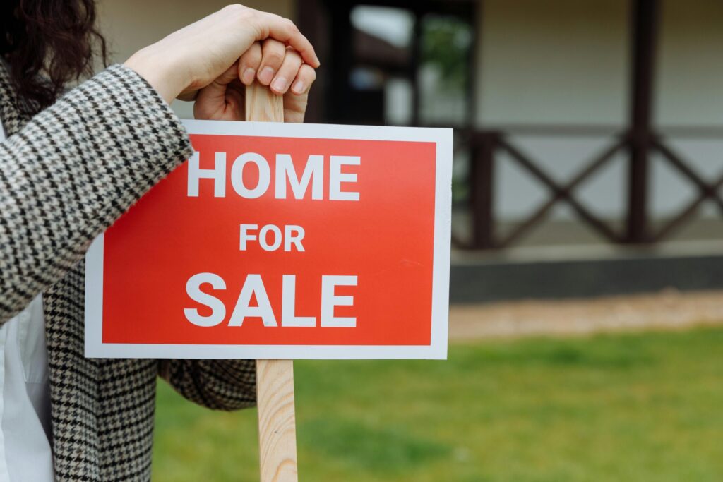 a person installing a homes for sale sign on the front yard